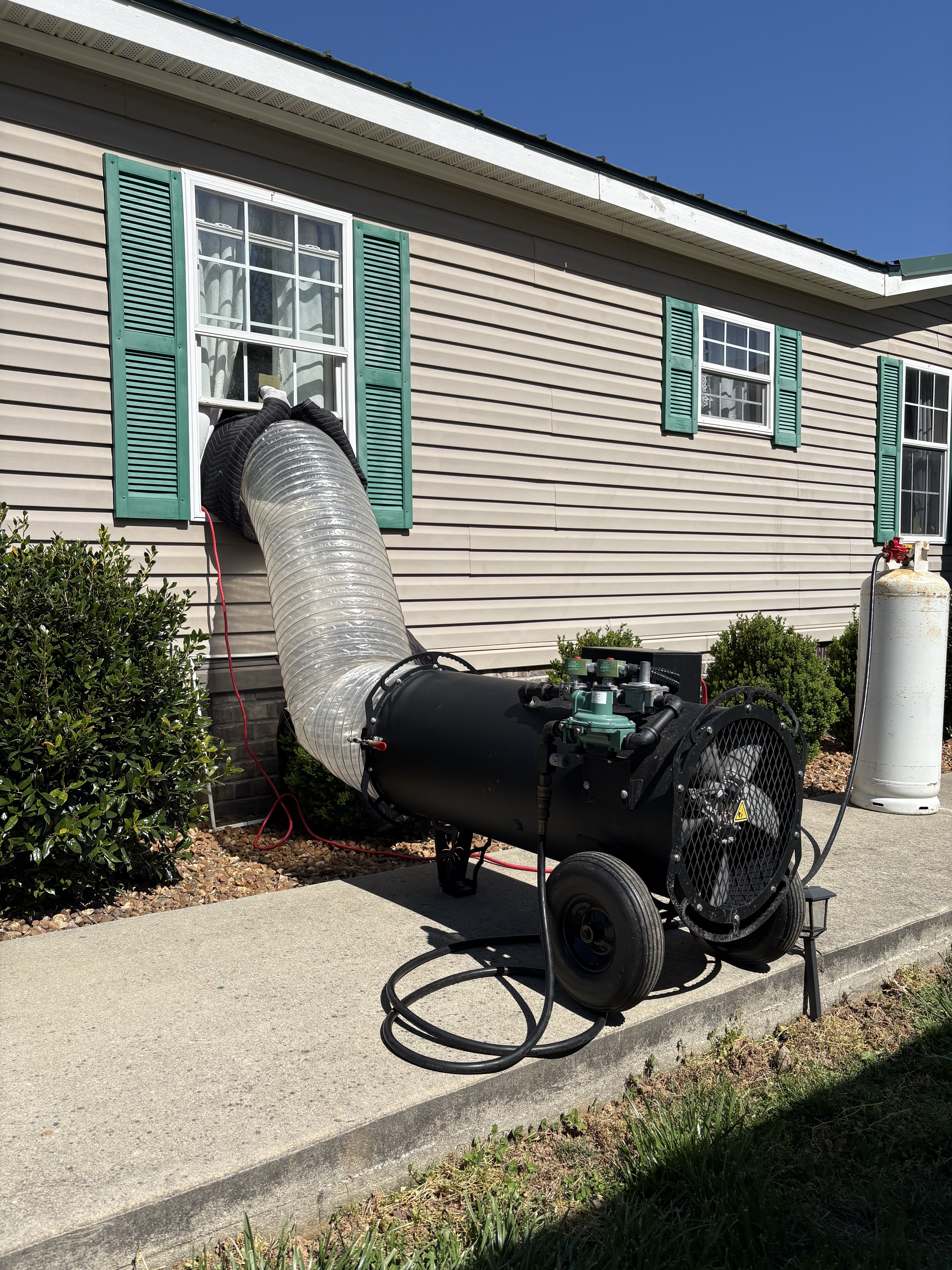 EcoForce heater and duct line entering a side window of a Nashville-area home with green shutters
