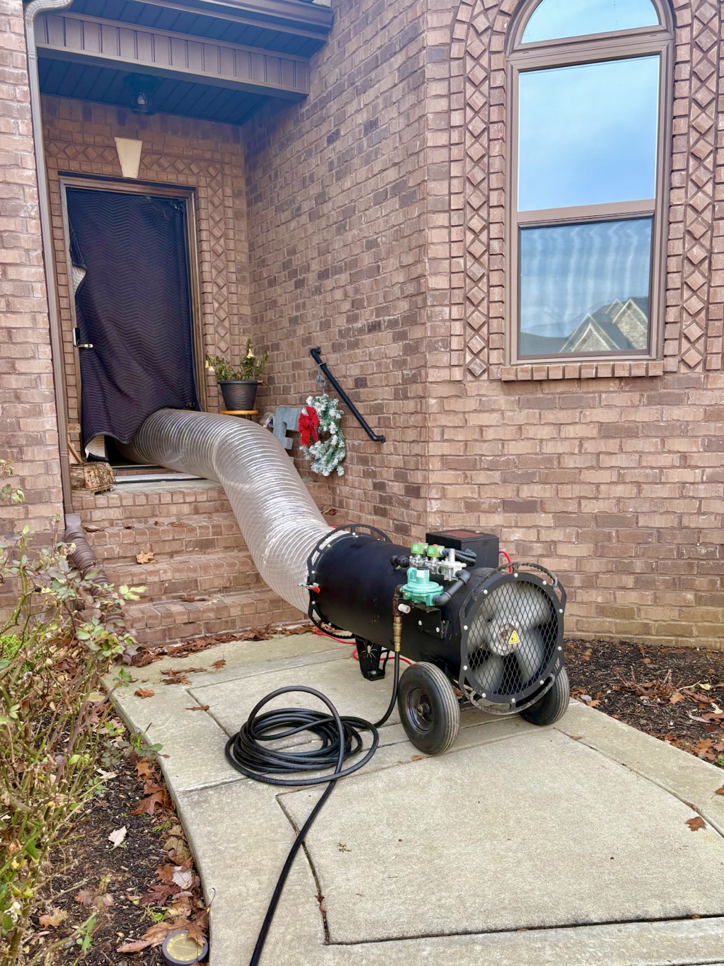 EcoForce treatment hose feeding through the front door of a brick home